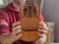 Close-up of a charango held by a musician in a red plaid shirt