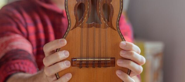 Close-up of a charango held by a musician in a red plaid shirt